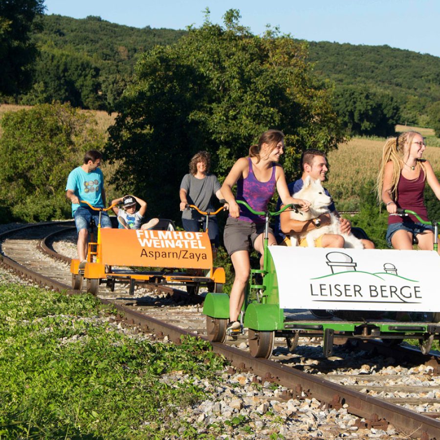 Familien fahren auf zwei Weinviertler Draisinen die Schienen entlang der Leiser Berge.